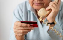 Senior woman using phone while holding credit card.
