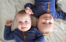 Identical twins lying upside down on white blanket