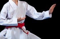 Aikido red belt on white kimono on black background.