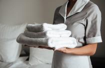 young-hotel-maid-standing-holding-fresh-clean-towels_171337-12687