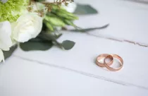 wedding-rings-with-white-roses-on-wooden-table_155003-997
