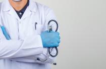 Doctor crossing arms while holding stethoscope in white coat fro