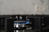 Modern kitchen stove, natural gas burns with a blue flame. Household gas consumption. Close-up, selective focus