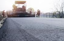 Workers placing new coating of asphalt on the road.