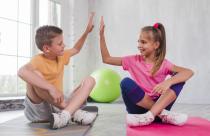 boy-and-girl-sitting-on-exercise-mat-giving-high-five