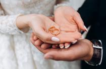 Groom holds bride's hands, where are two wedding rings