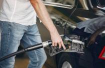 Handsome man pours gasoline into tank of car