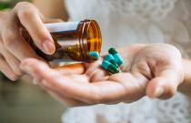 Woman's hand pours the medicine pills out of the bottle