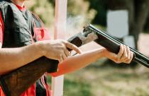 man opens the shotgun bolt after one shot with smoke