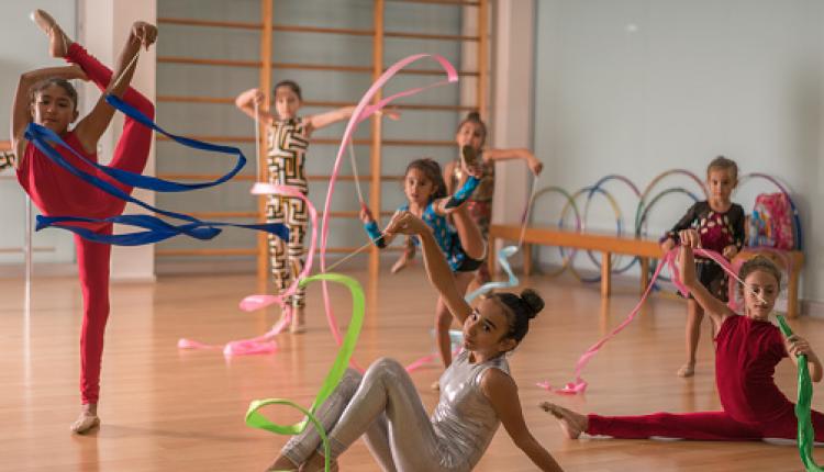 Young ballerinas dancing doing practice with ribbon in ballet studio.