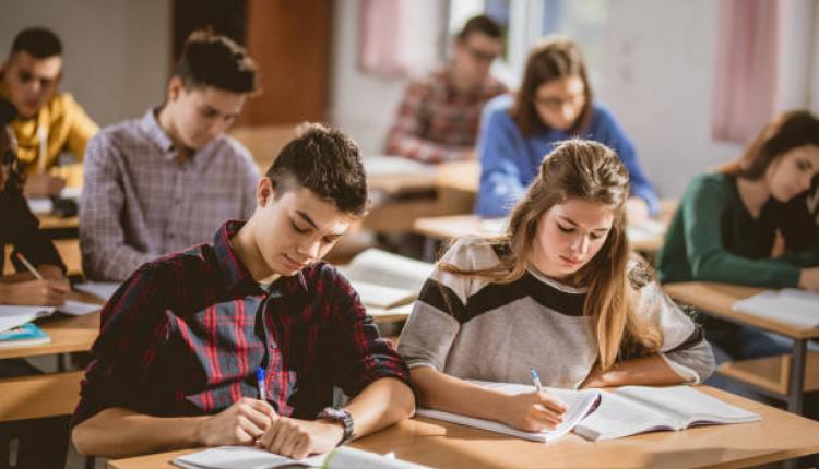 Large group of students writing an exam during a class in the classroom.