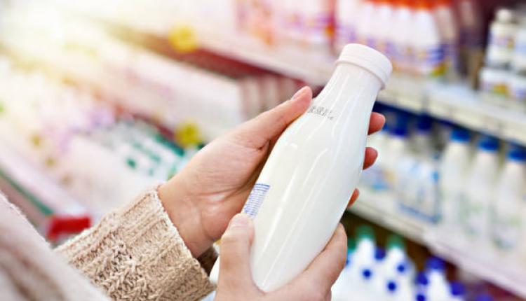 Buyer hands with a bottle of milk at the grocery store