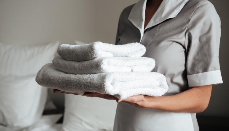 young-hotel-maid-standing-holding-fresh-clean-towels_171337-12687