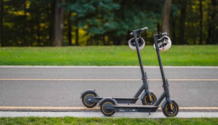 two electric kick scooters or e-scooter parked on the sidelines road