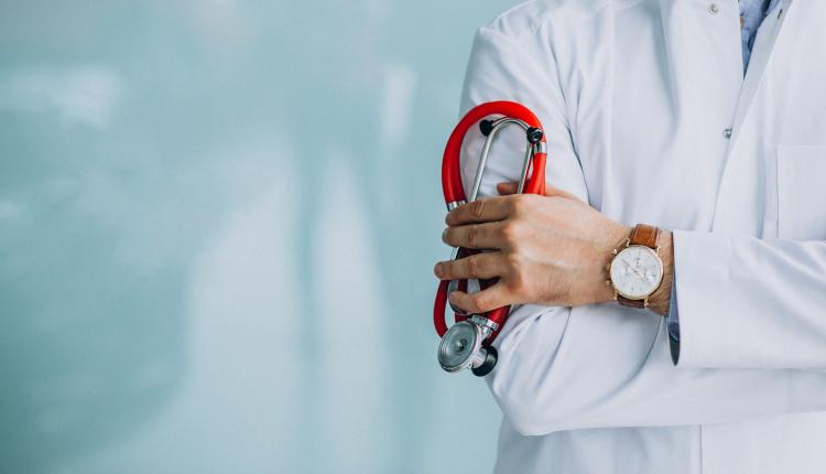 Young handsome physician in a medical robe with stethoscope