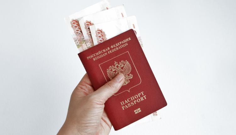 Hand holding Russian passport with 5000 rubles banknotes