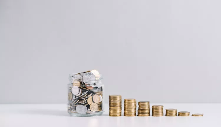 glass-jar-full-of-money-in-front-of-decreasing-stacked-coins-against-white-background_23-2147919228