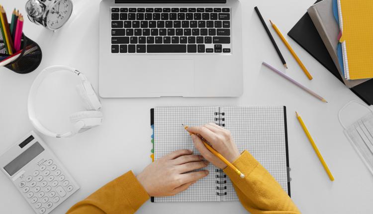 close-up-hand-writing-on-notebook-top-view