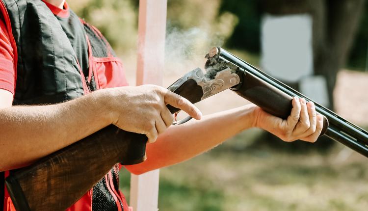 man opens the shotgun bolt after one shot with smoke