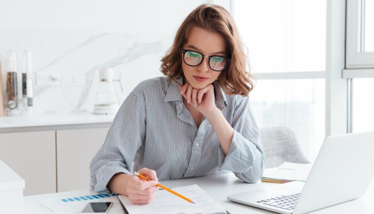 Young concentrated businesswoman in glasses and striped shirt wo