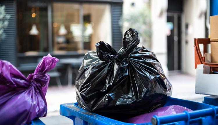 And black bags of trash on a garbage bin during daytime