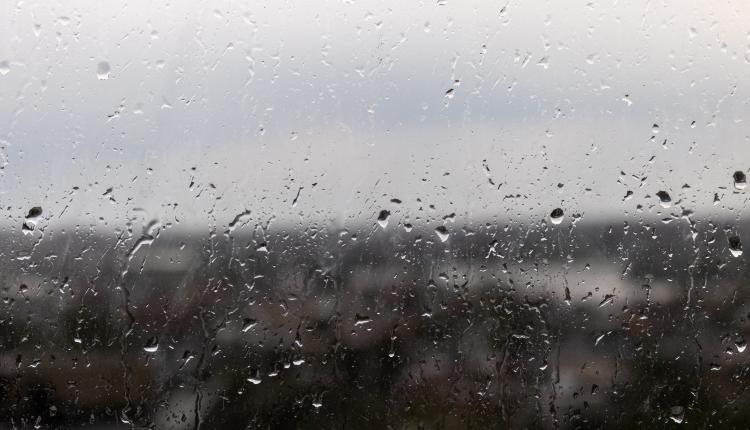 Closeup shot of a window on a rainy gloomy day, raindrops rolling down the window