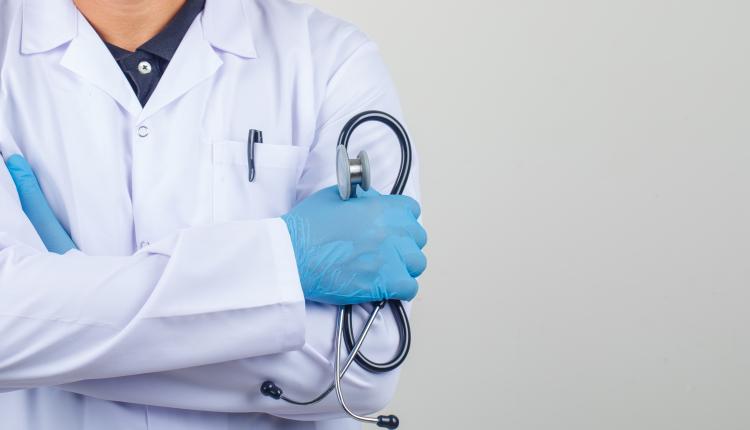 Doctor crossing arms while holding stethoscope in white coat fro