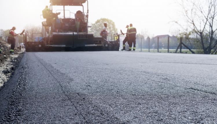 Workers placing new coating of asphalt on the road.