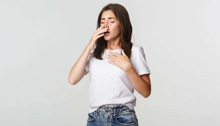 Young woman with allergy sneezing. Girl feeling sick having runny nose