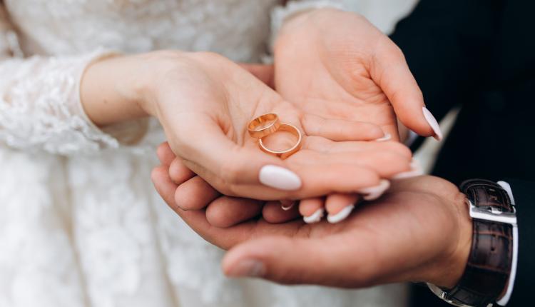 Groom holds bride's hands, where are two wedding rings