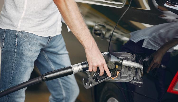 Handsome man pours gasoline into tank of car