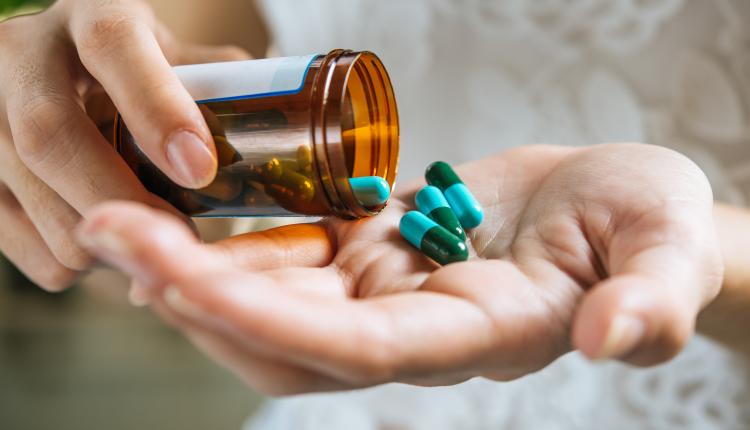 Woman's hand pours the medicine pills out of the bottle