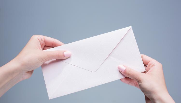The female hands with envelope against the gray background
