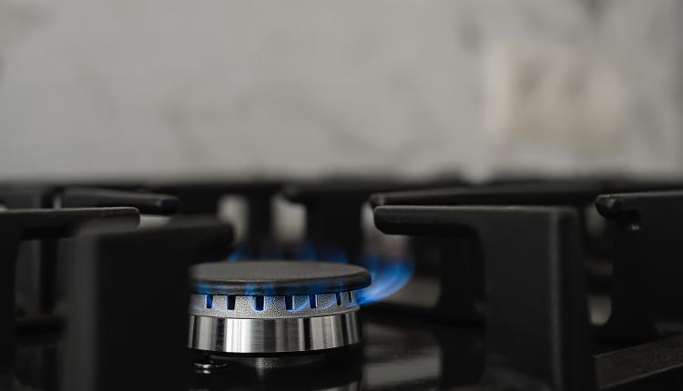 Modern kitchen stove, natural gas burns with a blue flame. Household gas consumption. Close-up, selective focus