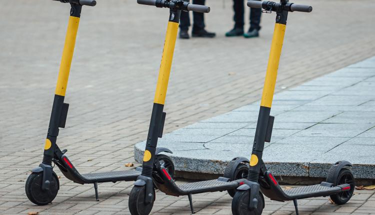 Selective focus shot of three electric scooters on the sidewalk